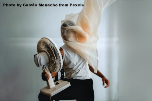 man with silky fabric over his head holding a fan toward himself